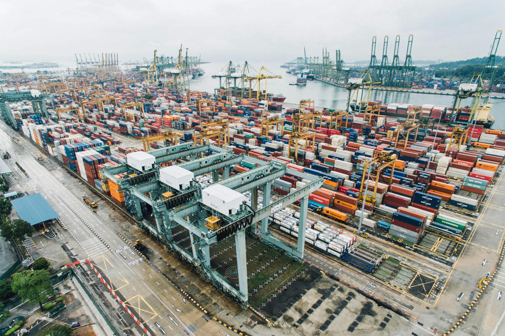 Aerial view of a busy container port with numerous shipping containers and cranes.