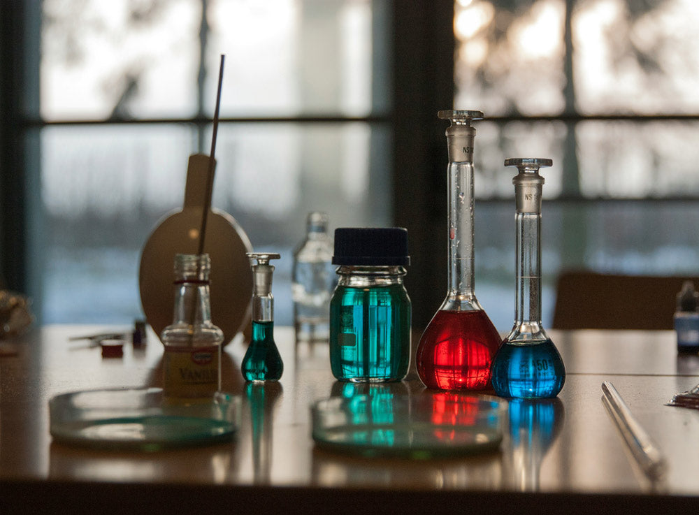 Laboratory setting with beakers containing colored liquids on a table.