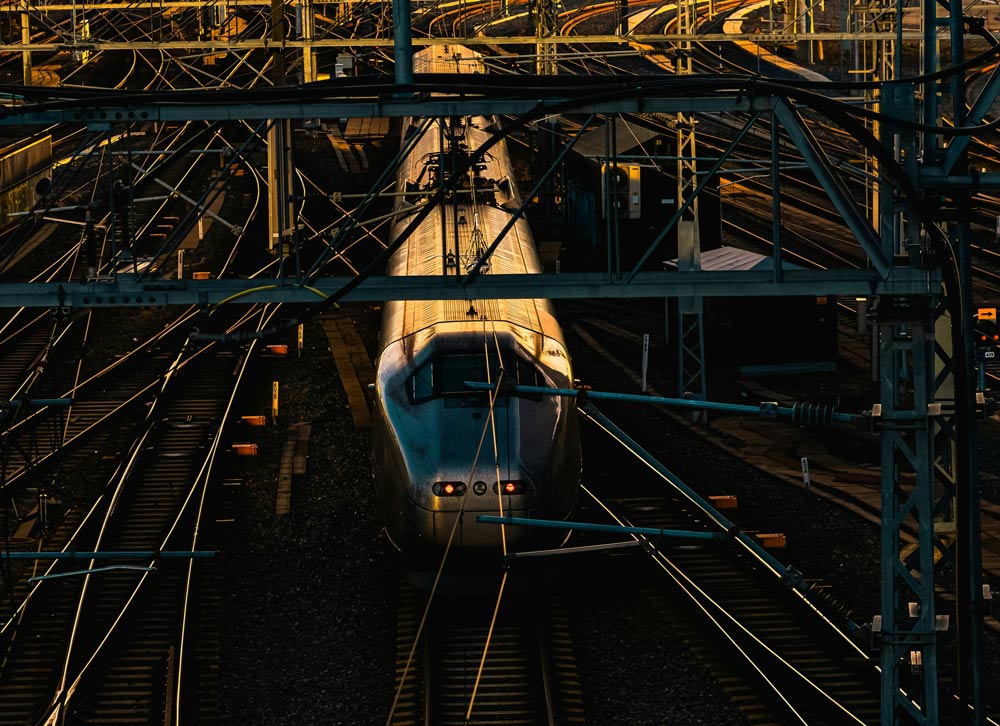 Train on tracks under a network of metal beams at night