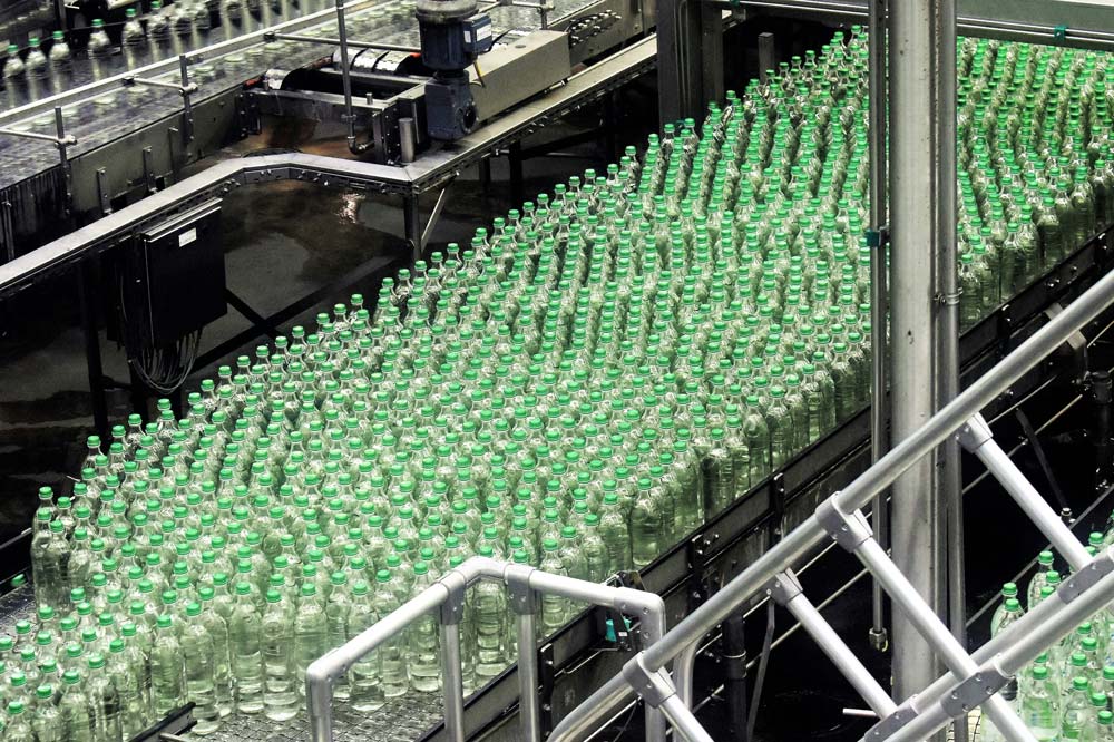 Conveyor belt with green bottles in a factory setting